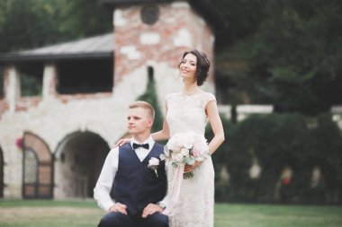 Yeni evli çiftimiz düğün günlerinde ellerinde buketle parkta yürüyorlar.