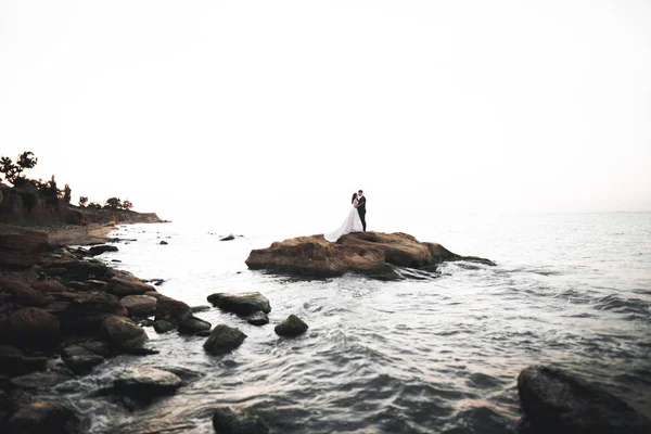 Boda pareja, novio, novia con ramo posando cerca del mar y el cielo azul —  Fotos de Stock