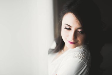 Cüppeli muhteşem gelin bir odada düğün töreni için poz veriyor ve hazırlanıyor.