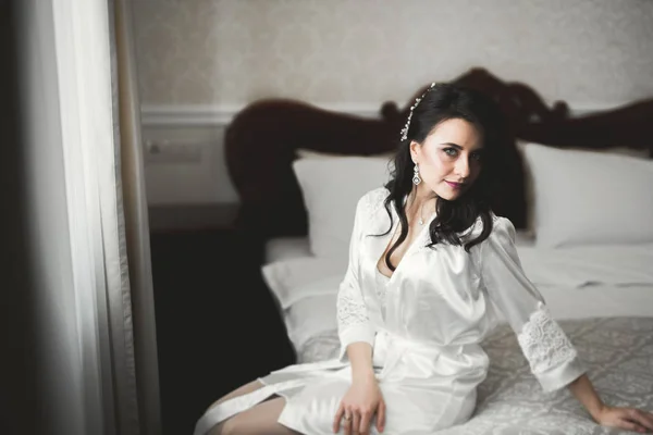 Gorgeous bride in robe posing and preparing for the wedding ceremony face in a room — Stock Photo, Image