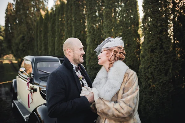 Happy newlywed couple, man and wife kissing near stylish retro car — Stock Photo, Image