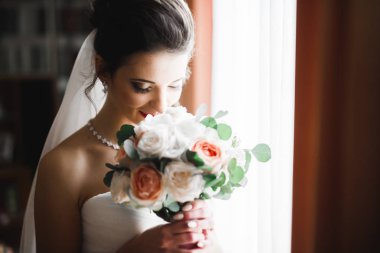 Beyaz elbiseli lüks gelin düğün törenine hazırlanırken poz veriyor.