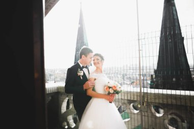 Güzel bir düğün çifti eski kasabanın arka plan panoramik manzarasında öpüşüp sarılıyor.