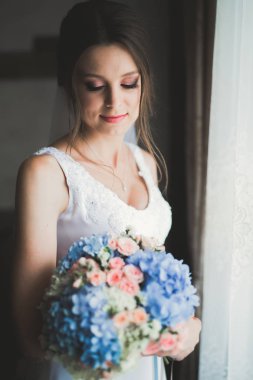 Beyaz elbiseli lüks gelin düğün törenine hazırlanırken poz veriyor.