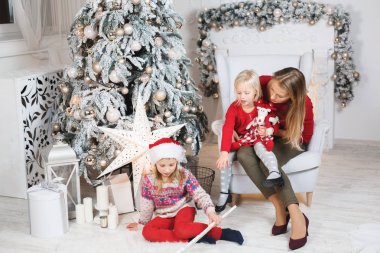 Anne ve çocukları Noel ağacının yanında kutluyorlar.