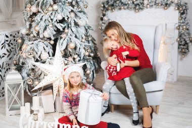 Anne ve kızları küçük kızların doğum günü hediyelerini açıyorlar.