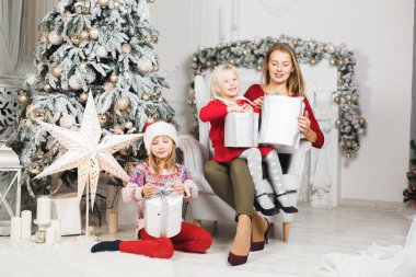 Anne ve kızları küçük kızların doğum günü hediyelerini açıyorlar.