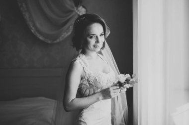 Cüppeli muhteşem gelin bir odada düğün töreni için poz veriyor ve hazırlanıyor.