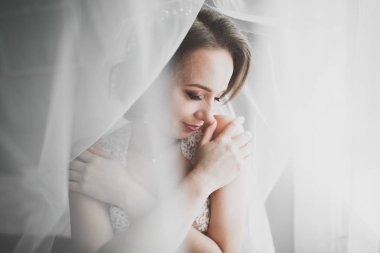 Cüppeli muhteşem gelin bir odada düğün töreni için poz veriyor ve hazırlanıyor.