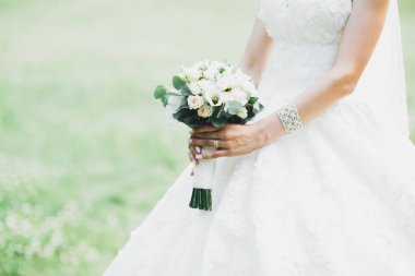 Çekici gelinin portresi, uzun saçlı, büyük buketli poz veren.