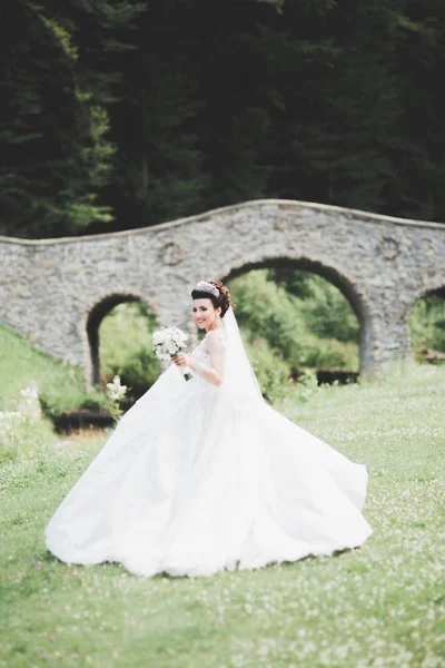 Linda noiva jovem de luxo em vestido de noiva posando no parque — Fotografia de Stock