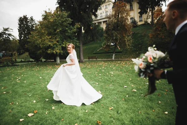 Romántico, cuento de hadas, feliz pareja recién casada abrazándose y besándose en un parque, árboles en el fondo —  Fotos de Stock