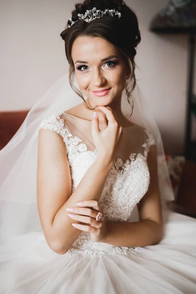 Hermosa novia con vestido de novia de moda con plumas con maquillaje de lujo deleite y peinado, estudio sesión de fotos interior — Foto de Stock