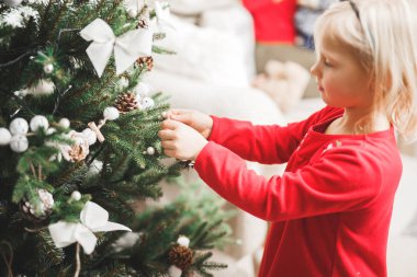 Güzel bir Noel ağacını süsleyen mutlu kız.
