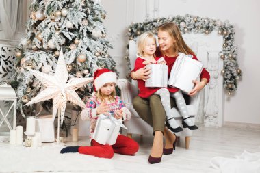 Anne ve kızları küçük kızların doğum günü hediyelerini açıyorlar.