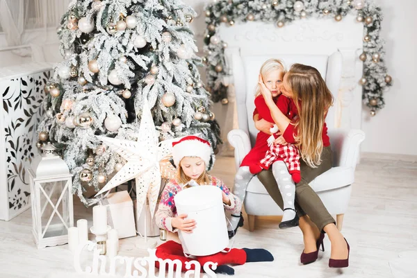 Madre con sus hijas pequeñas celebrando cerca del árbol de Navidad — Foto de Stock