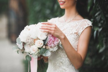 Gelin çiçekli büyük ve güzel bir düğün buketi tutuyor.