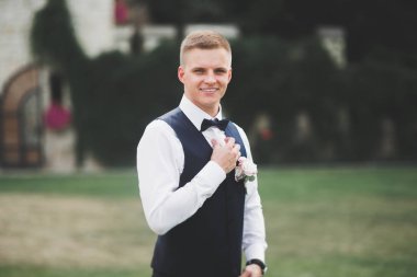 Yaka çiçeğiyle poz veren mutlu yakışıklı damat.