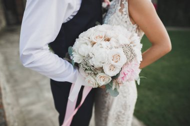 Gelin çiçekli büyük ve güzel bir düğün buketi tutuyor.