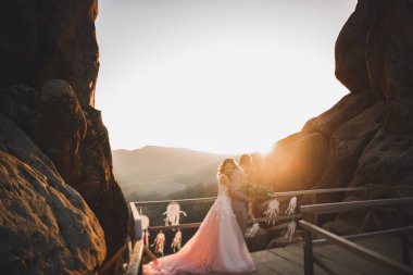 Harika bir gelin damada poz veriyor ve harika manzaralı dağlarda lüks bir tören yapıyor.