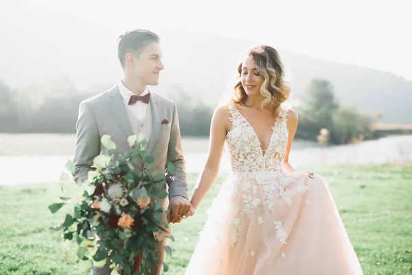 Güzel bir düğün çifti, gelin ve damat gün batımında sahada poz veriyorlar.