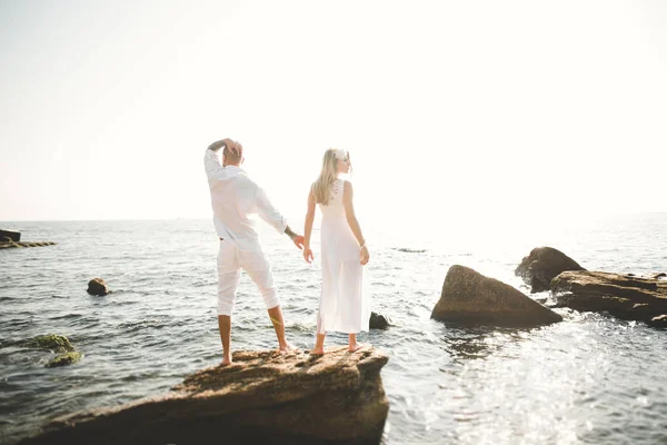 Щасливі щойно одружилися молода весільна пара святкує і розважається на красивому пляжному заході сонця — стокове фото