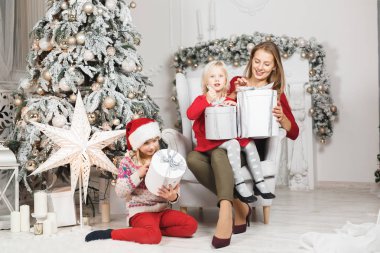 Anne ve çocukları Noel ağacının yanında kutluyorlar.