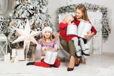 Anne ve kızları küçük kızların doğum günü hediyelerini açıyorlar.