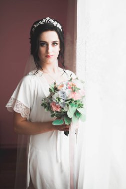 Beyaz elbiseli lüks gelin düğün törenine hazırlanırken poz veriyor.