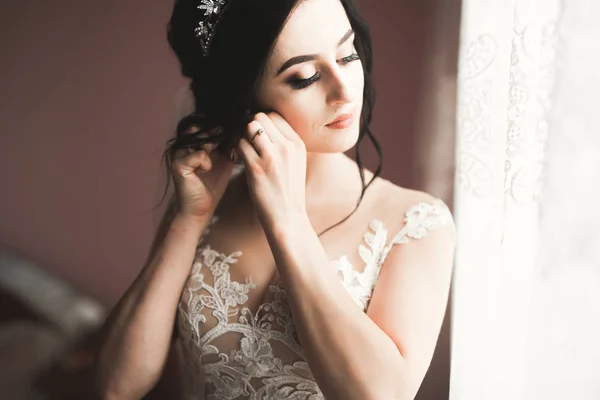 Noiva de luxo em vestido branco posando enquanto se prepara para a cerimônia de casamento — Fotografia de Stock