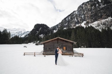 Kış dağlarında güzel genç bir çift. Aşıkların kış yürüyüşü. Erkek kadına sarılıyor.