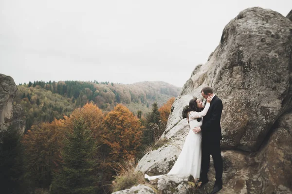 Casamento casal no amor beijando e abraçando perto de pedras na bela paisagem — Fotografia de Stock