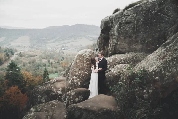 Wedding couple in love kissing and hugging near rocks on beautiful landscape — Stock Photo, Image