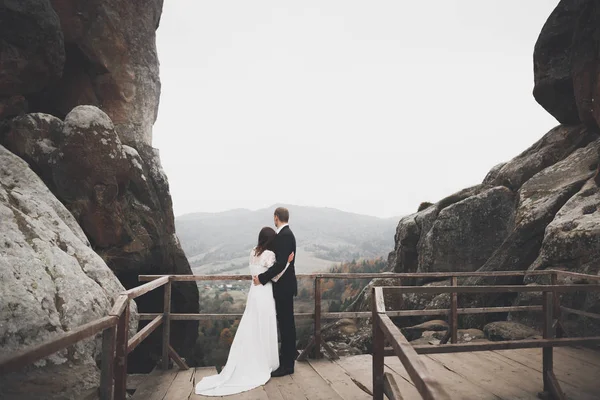 Весільна пара в любові цілується і обіймається біля скель на красивому пейзажі — стокове фото