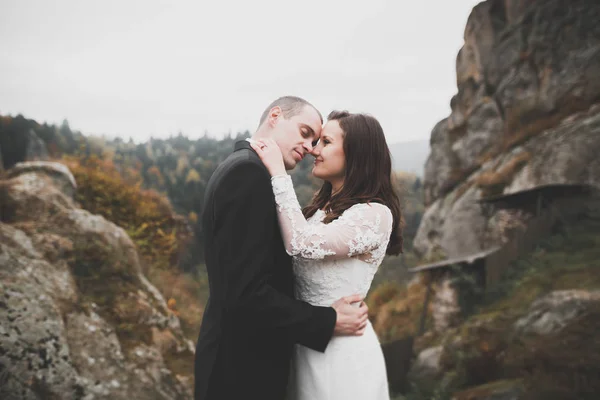 Verliebtes Hochzeitspaar küsst und umarmt sich in der Nähe von Felsen in schöner Landschaft — Stockfoto
