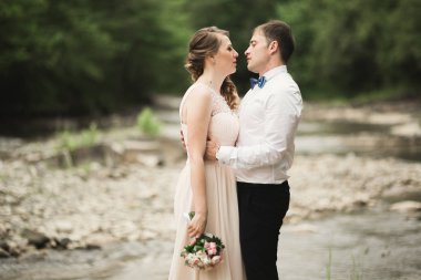 Zarif nazik şık damat ve gelin taşlarla Nehri yakınında. Evlilik çift aşık