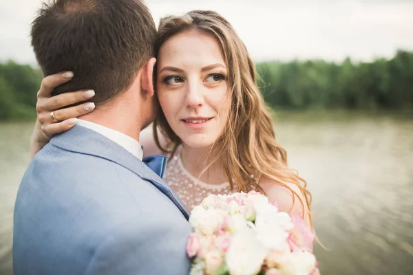Sposa e sposo in possesso di bel bouquet da sposa. Lago, foresta — Foto Stock