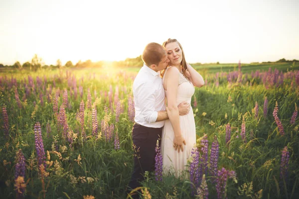 Jeune couple de mariage marchant sur le terrain avec des fleurs — Photo