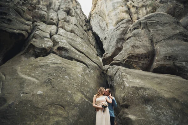 Feliz boda pareja besándose y abrazándose cerca de un alto acantilado — Foto de Stock