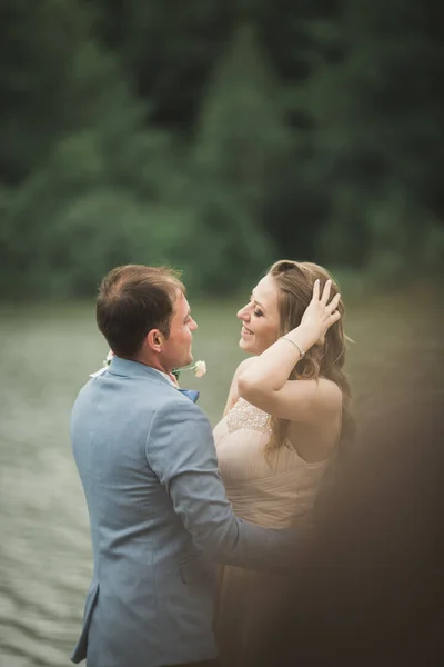 Beautiful wedding couple, bride,groom kissing and posing on the bridge near lake — Stock Photo, Image