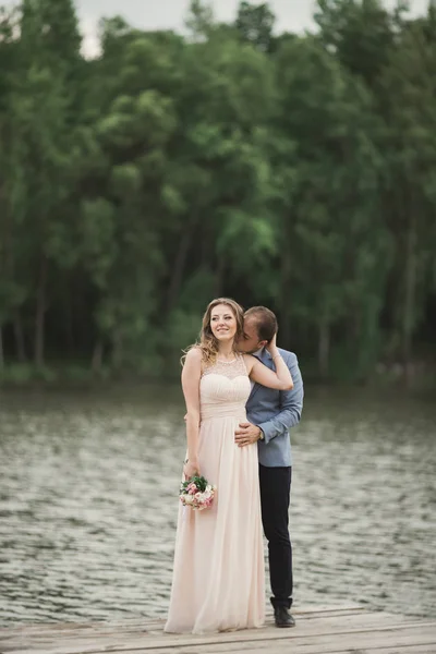 夕暮れ時に湖の近くポーズ エレガントな美しい結婚式のカップル — ストック写真