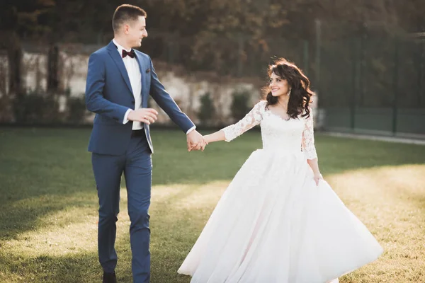 Romantisches, märchenhaftes, glückliches Brautpaar, das sich im Park umarmt und küsst, Bäume im Hintergrund — Stockfoto