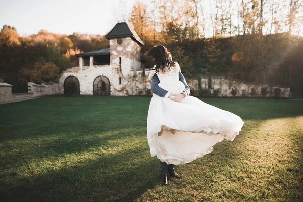 Romántico, cuento de hadas, feliz pareja recién casada abrazándose y besándose en un parque, árboles en el fondo — Foto de Stock