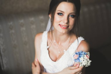 Cüppeli muhteşem gelin bir odada düğün töreni için poz veriyor ve hazırlanıyor.