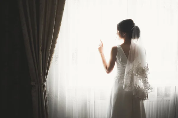 Preciosa novia en bata posando y preparándose para la ceremonia de boda cara en una habitación — Foto de Stock