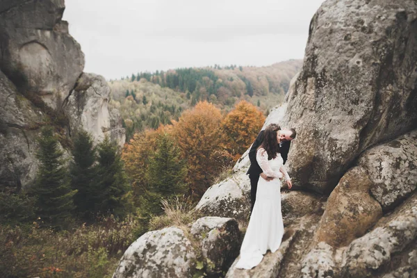 Pareja feliz boda posando sobre hermoso paisaje en las montañas — Foto de Stock