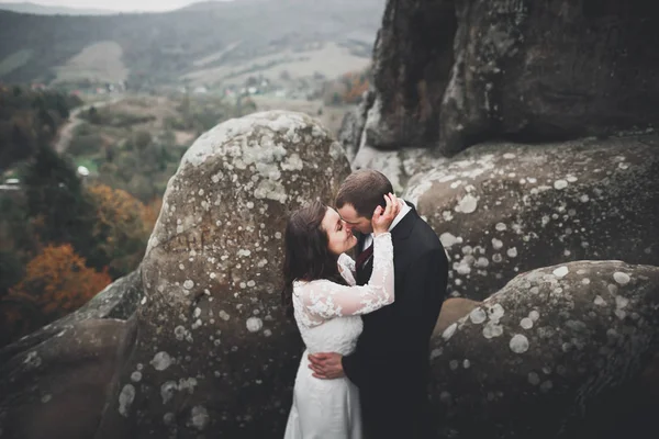Счастливая супружеская пара позирует над красивым пейзажем в горах — стоковое фото