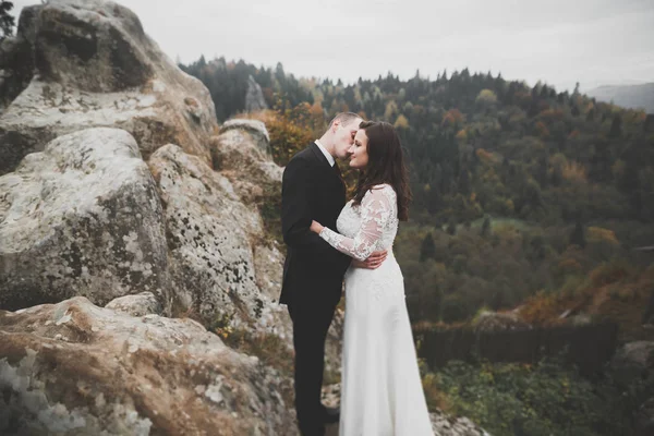 Joyeux beau couple de mariage mariée et marié le jour du mariage à l'extérieur sur le rocher des montagnes. Couple mariage heureux en plein air sur la nature, douces lumières ensoleillées — Photo