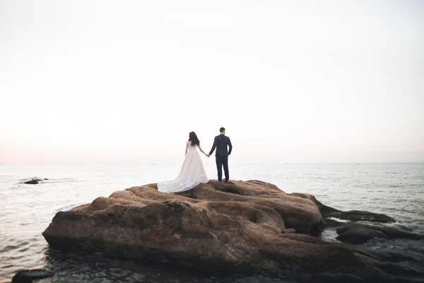 Hochzeitspaar, Bräutigam, Braut mit Strauß posiert in der Nähe des Meeres und des blauen Himmels — Stockfoto