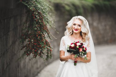 Parkta poz veren zarif beyaz elbiseli güzel gelin.